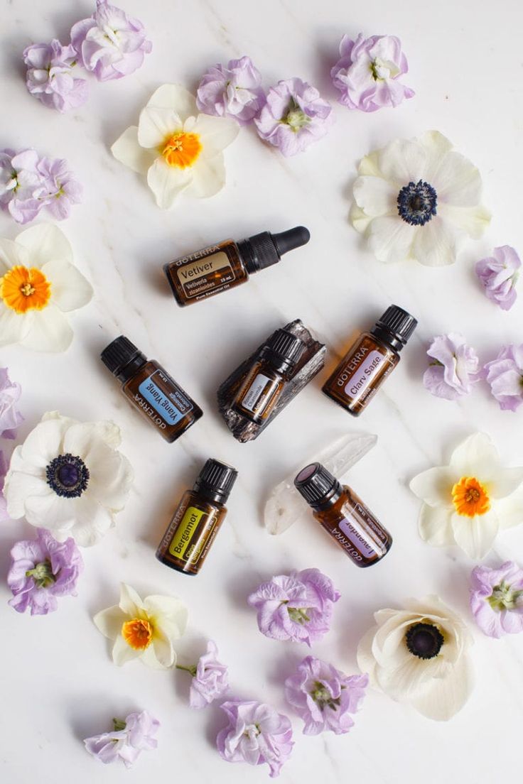 an assortment of essential oils and flowers on a white surface with purple and yellow petals