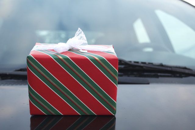 a wrapped christmas present sitting on top of a black table in front of a car