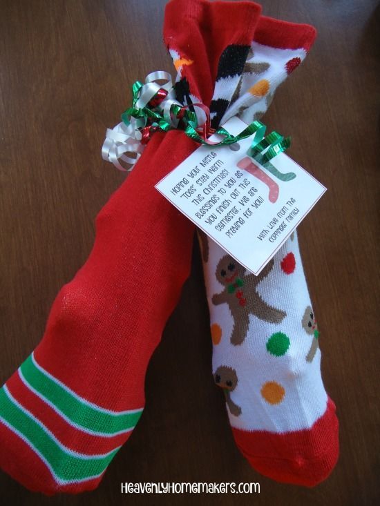 two christmas stockings tied to each other on top of a wooden table with a tag attached