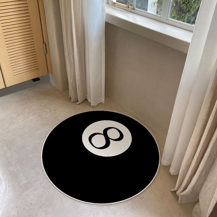 a black and white round rug with the letter o on it in front of a window