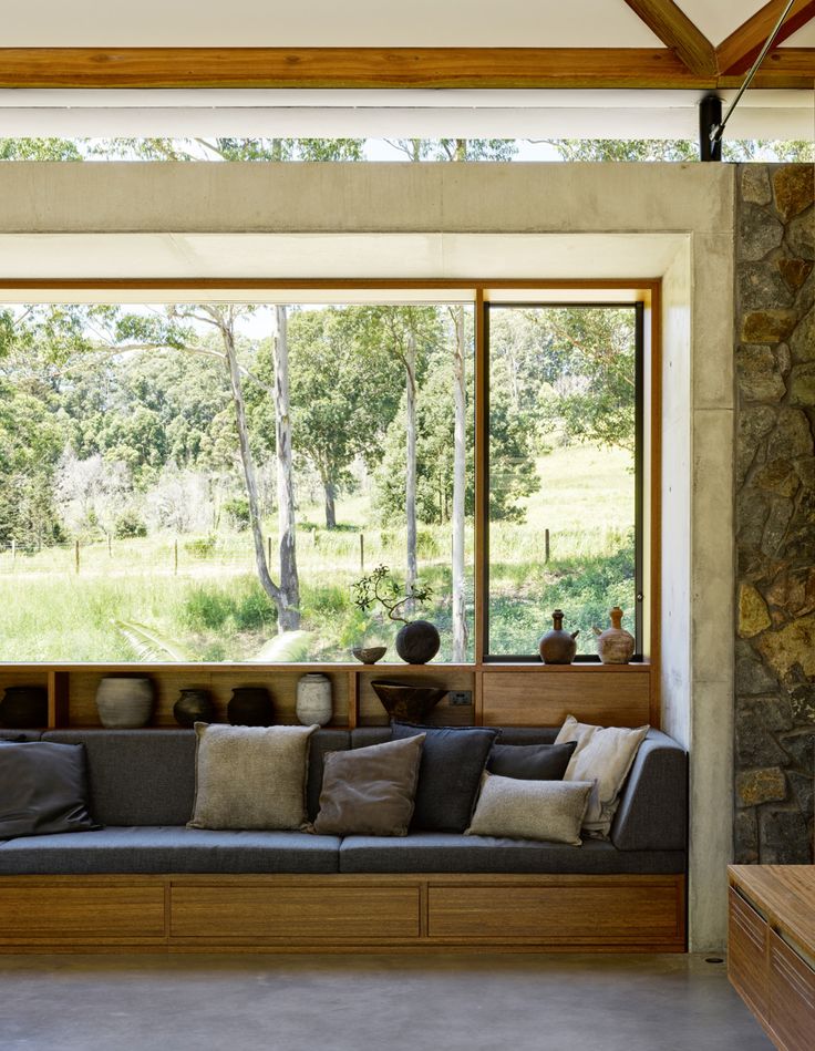 a living room filled with lots of furniture next to a stone wall covered in windows