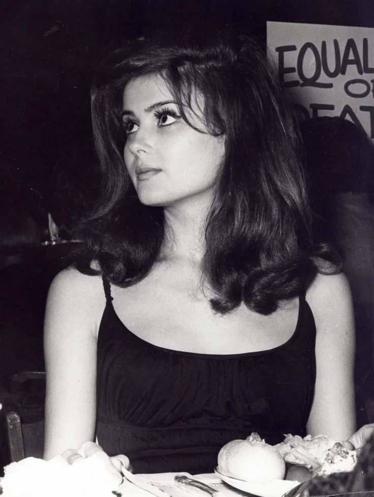 a woman sitting at a table with food in front of her and looking off to the side