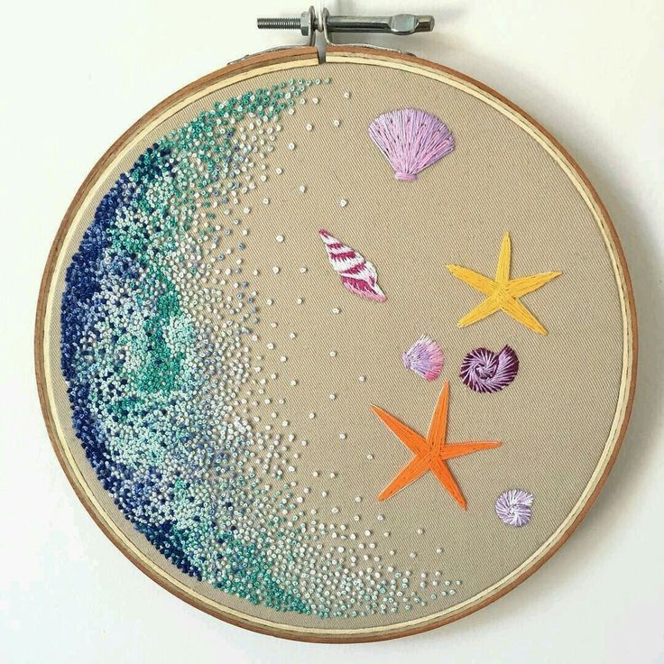 an embroidery project with starfish, shells and seashells hanging on a wall