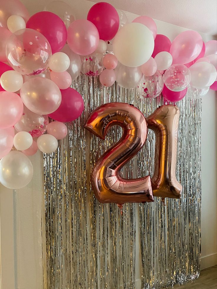 balloons and streamers are hanging from the ceiling in front of a large number twenty sign