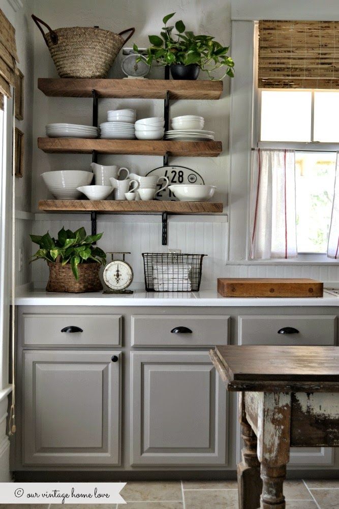 a kitchen with gray cabinets and shelves filled with dishes