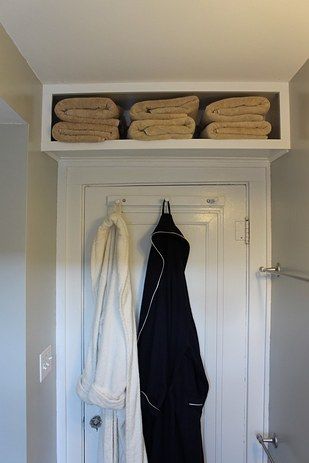 an image of a closet with towels and clothes hanging on the door shelf above it