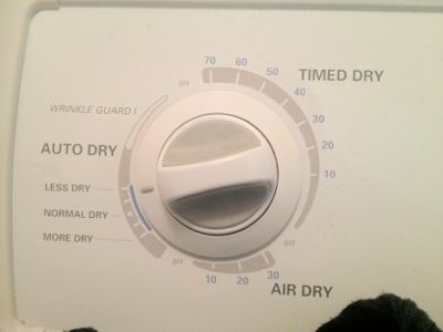 a person standing in front of a dryer with the control panel on it's side