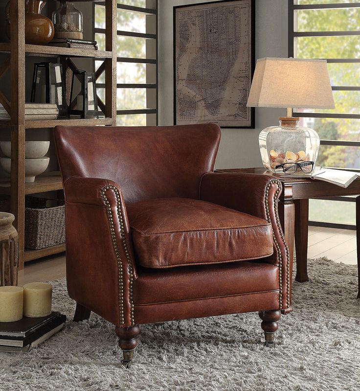 a brown leather chair sitting on top of a rug next to a table and lamp