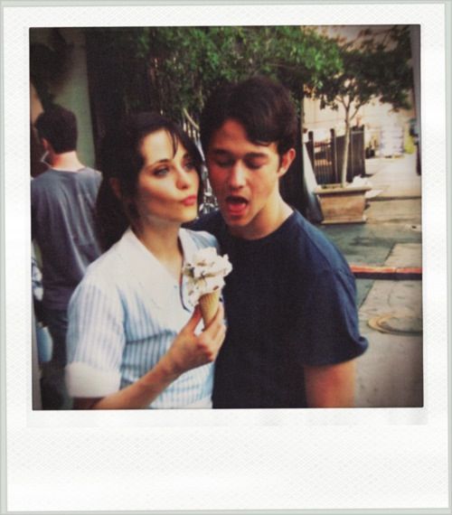 a young man and woman standing next to each other holding an ice cream sundae