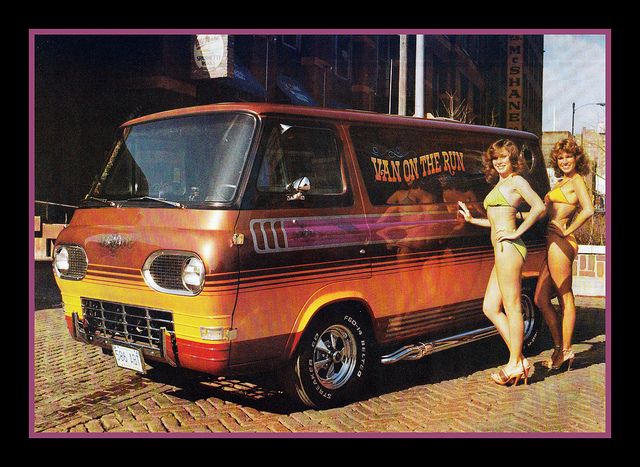 two women in bathing suits standing next to an old van with the word hot on it