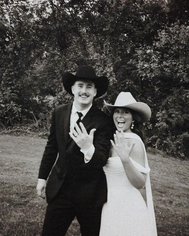 a man and woman dressed up in wedding attire posing for the camera with trees behind them