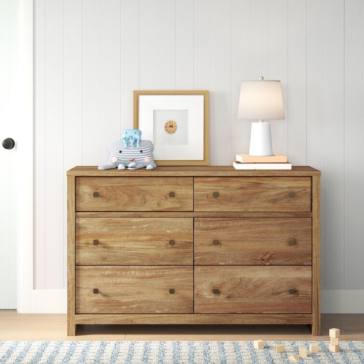 a wooden dresser sitting next to a white door in a room with a blue and white rug on the floor