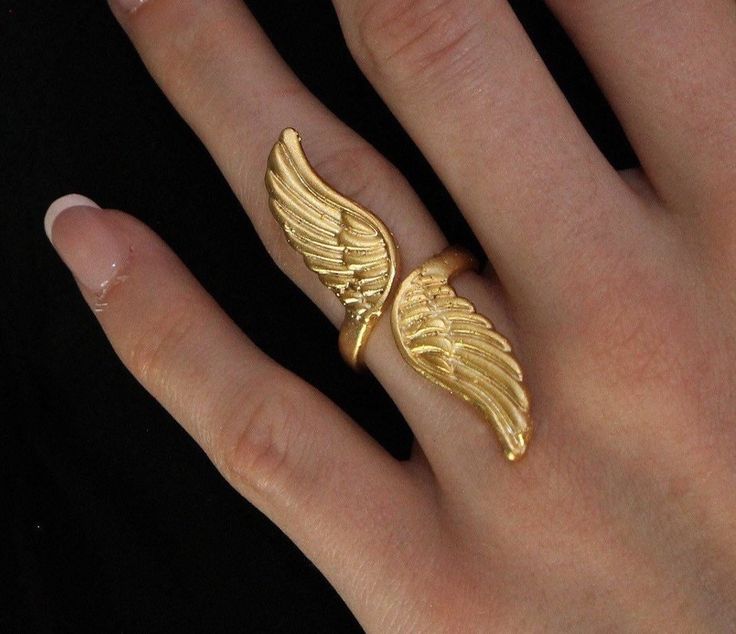 Gold Angel Wing Ring: ▪️  This gorgeous statement piece will make the perfect gift for yourself or a loved one. The ring is adjustable and will fit different finger sizes   ▪️  Made of gold plated brass   ▪️  The model in the picture is a size 7     Care Instructions:   ▪️  Gold plating can last for years if looked after correctly   ▪️  Keep away from water, sweat, chemicals, perfumes, lotions, etc. If it begins to tarnish in areas of high friction, the color will appear a darker orange   ▪️  How to clean: dip a cotton ball in a solution of mild dish soap and water. Rub gently and then rinse, dry, and buff     We hope you enjoy! We have family ties with jewelers in Istanbul, Turkey who hand make our pieces with love. Your happiness is our utmost priority, and we accept returns if it doesn' Wings Ring, Wing Ring, Angel Wing Ring, Angel Ring, Corporate Goth, Metal Wings, Gold Angel Wings, Ring Elegant, Gold Angel