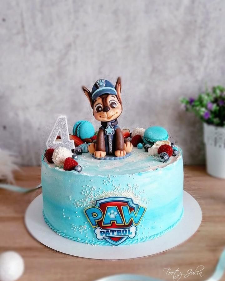 a blue cake with a dog on top sitting on a table next to some flowers