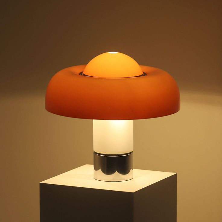 The Brumbry Table Lamp by Dekorfine is a perfect blend of modern design and vibrant color. Featuring a striking orange glass shade and a sleek metal base, this lamp adds a pop of color and contemporary style to any space. The smooth, rounded lines of the glass shade diffuse light beautifully, creating a warm and inviting atmosphere. Ideal for desks, bedside tables, or living room accents, the Brumbry Table Lamp enhances your decor with its unique aesthetic and high-quality craftsmanship. If you Iconic Table Lamp, Guzzini Lamp, Harvey Guzzini, Luigi Massoni, Orange Table Lamps, Desktop Lamp, Ingo Maurer, Orange Table, Luxury Lamps