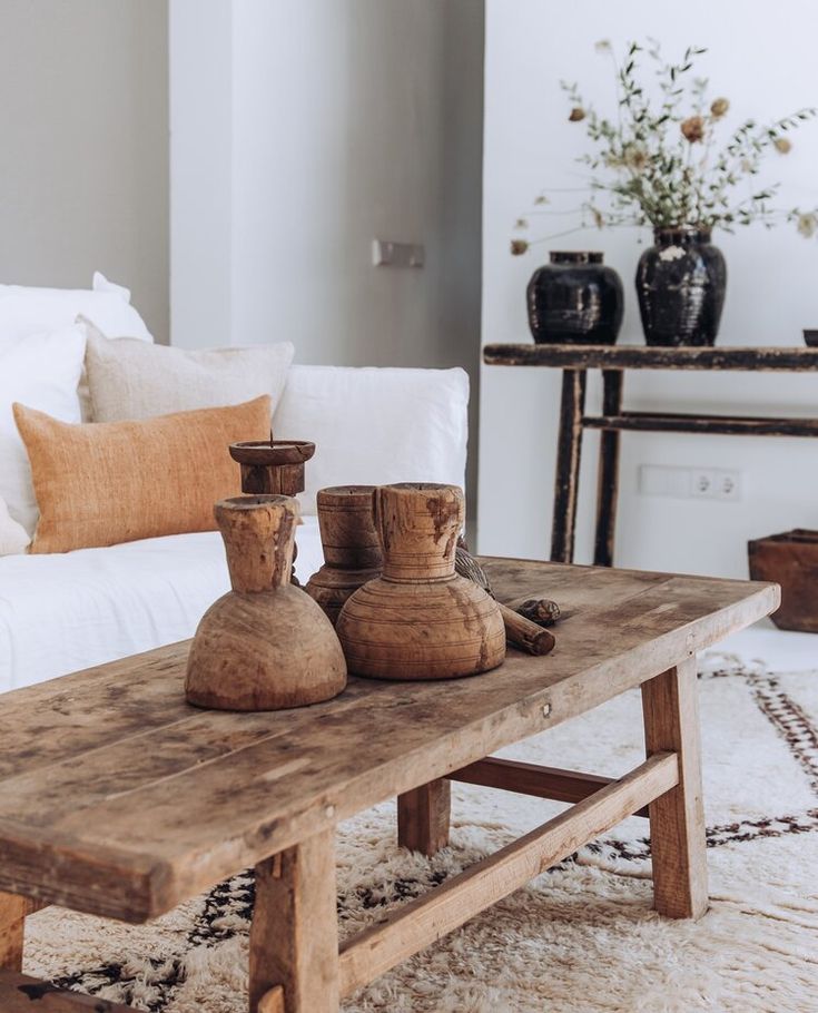 two wooden vases sitting on top of a table in front of a white couch