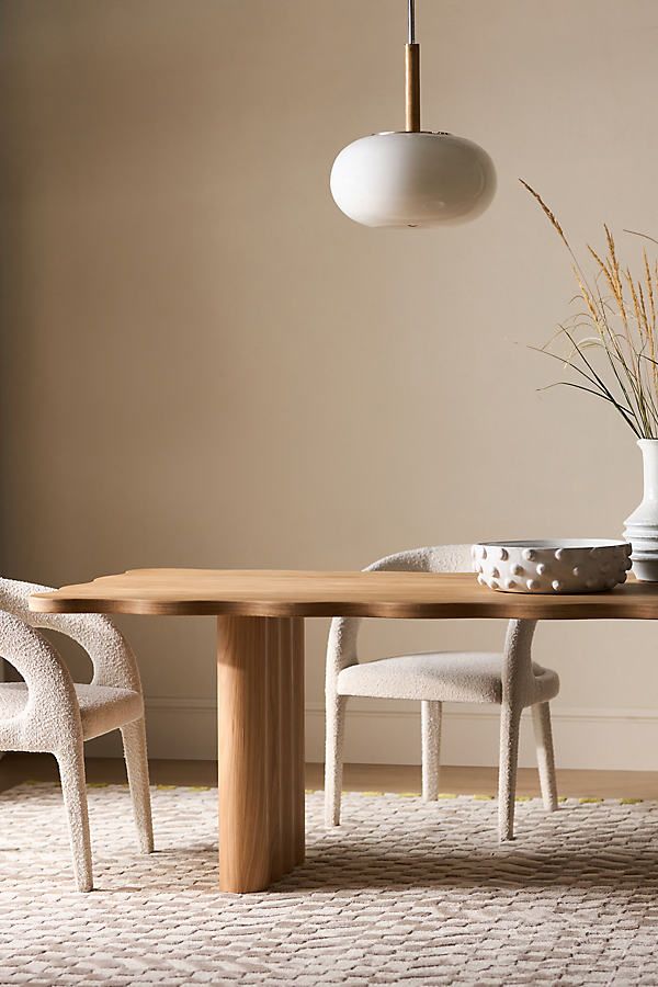 a dining room table with two chairs and a vase on the table next to it