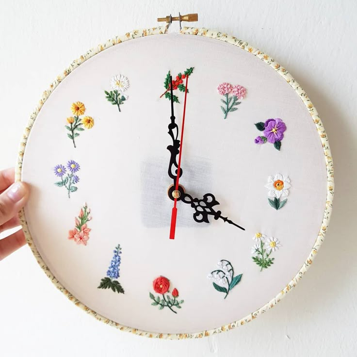 a hand holding a clock with flowers painted on it