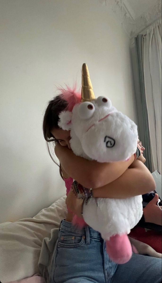 a woman is hugging a stuffed animal unicorn