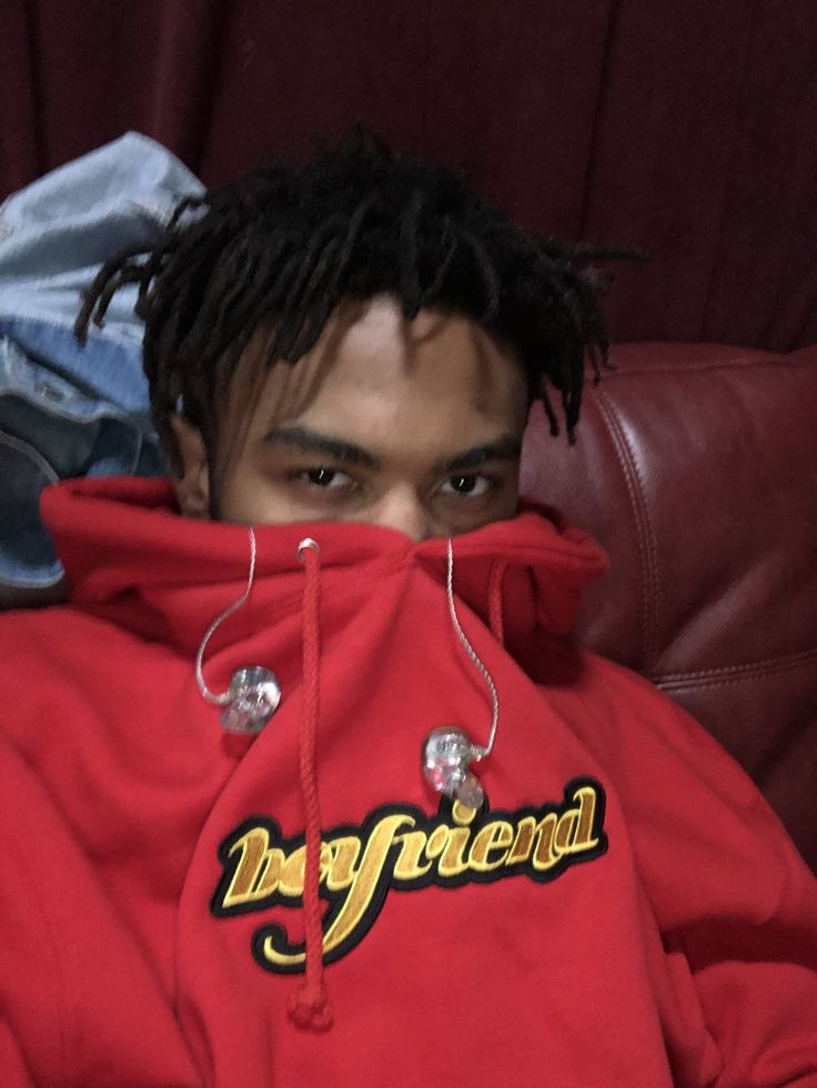 a young man with dreadlocks covering his face while sitting on a leather couch