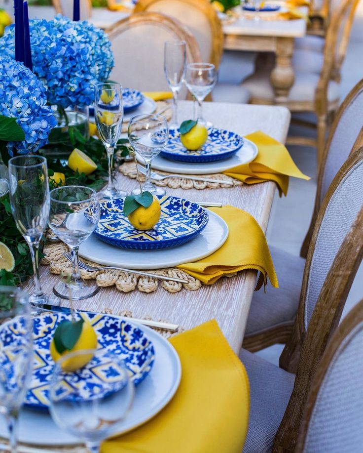 the table is set with blue and white plates, yellow napkins, and lemons