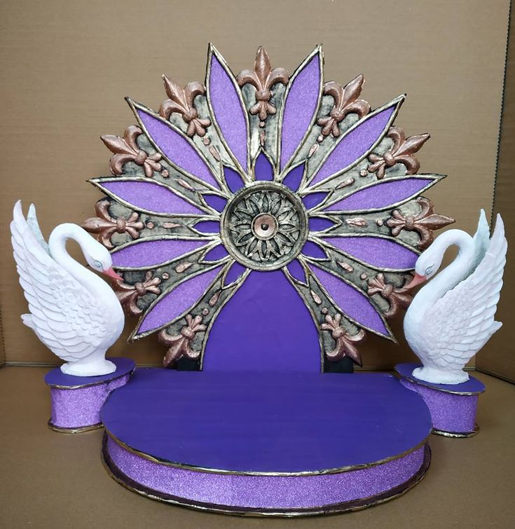 a purple clock with two white swans on it's sides and an ornate design