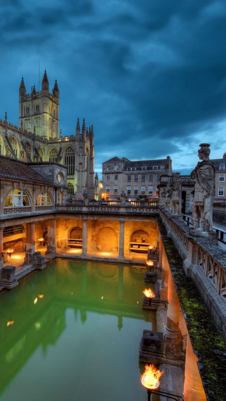 a large building with a pool in front of it and lit candles on the ground