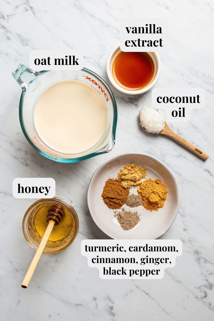 ingredients needed to make homemade cinnamon spice recipe on marble counter top with honey, oat milk, coconut oil and cocoa