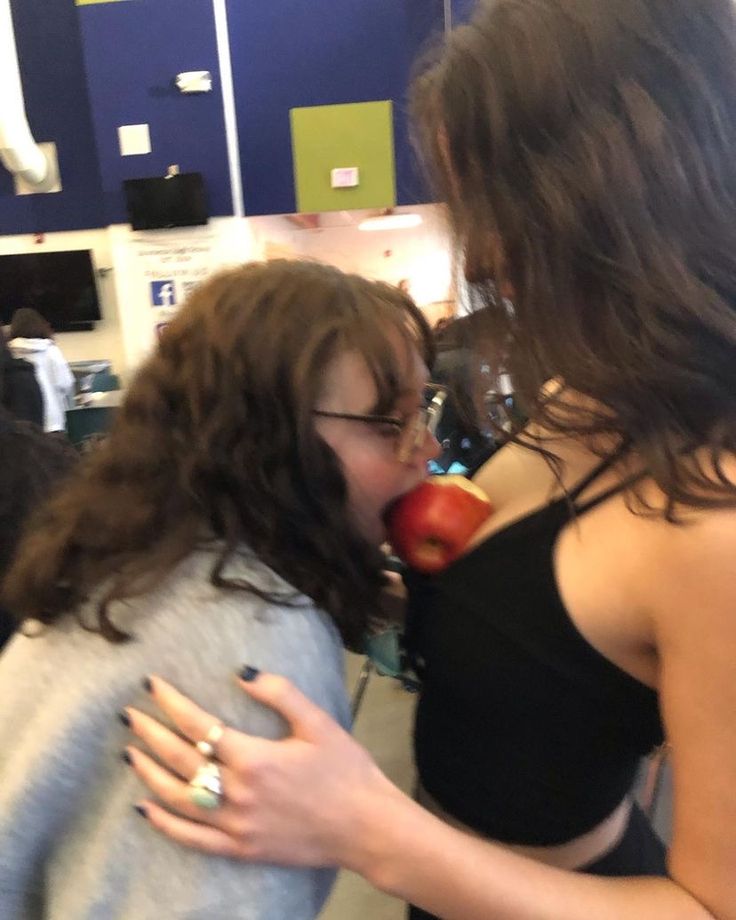 two young women are sharing an apple together