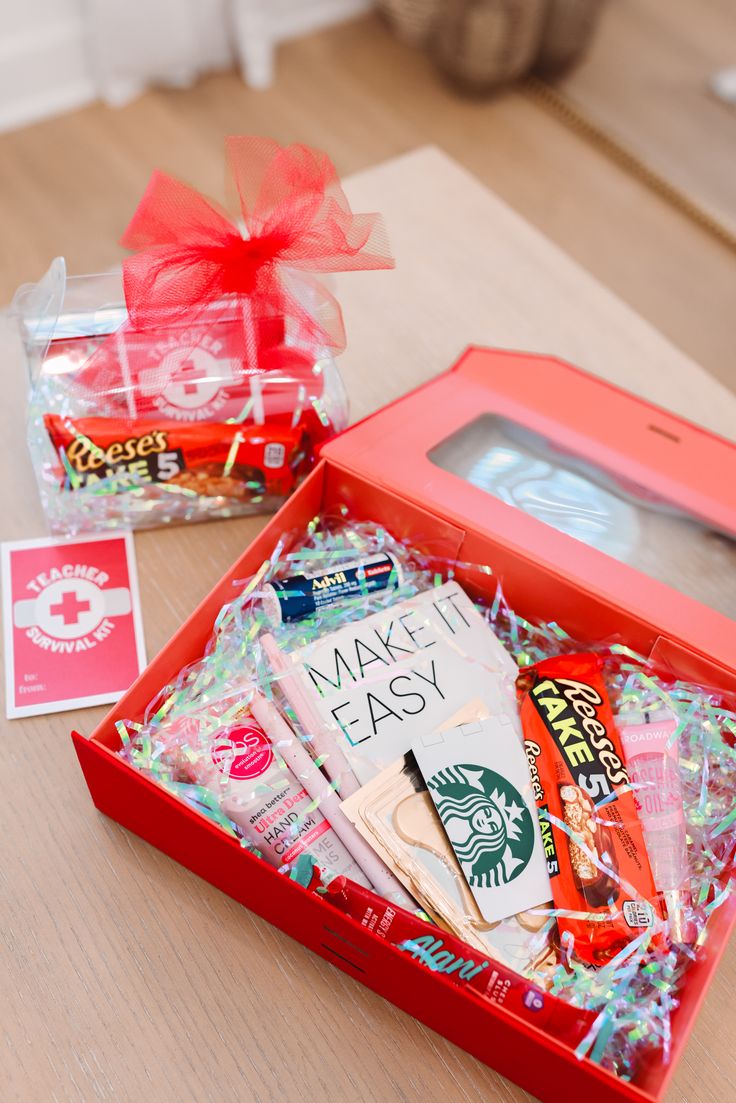 a red box filled with assorted items sitting on top of a wooden table next to a package