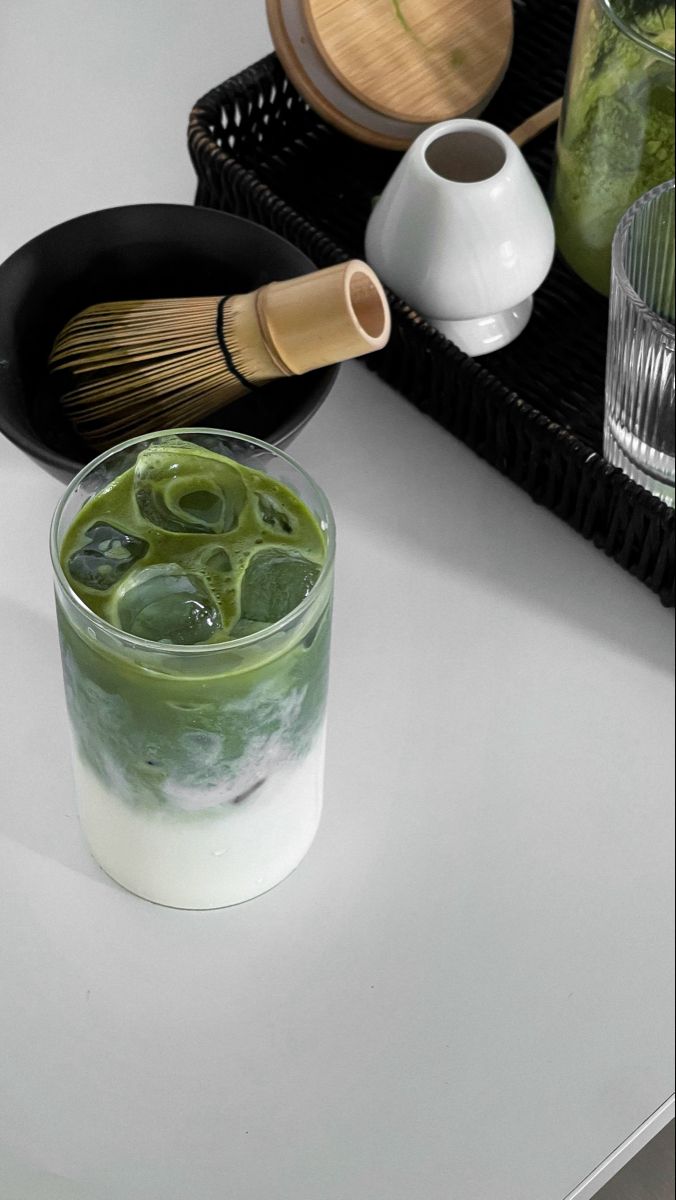 a glass filled with green liquid sitting on top of a table next to other items