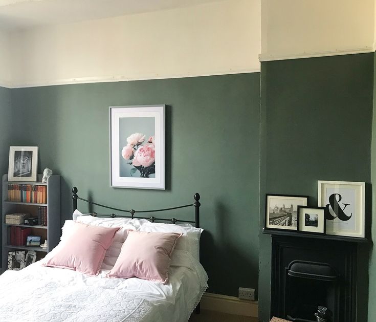 a bedroom with green walls, white bedding and pink pillows on the headboard