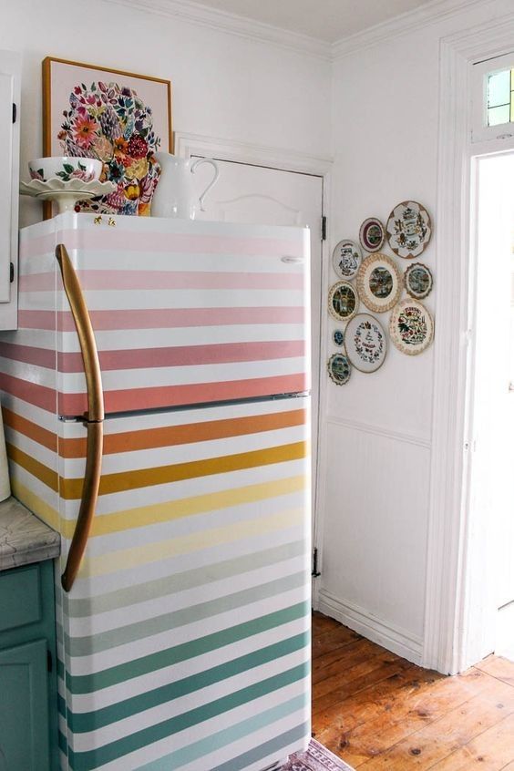 a colorful refrigerator in a kitchen with plates on the wall and door to the other side