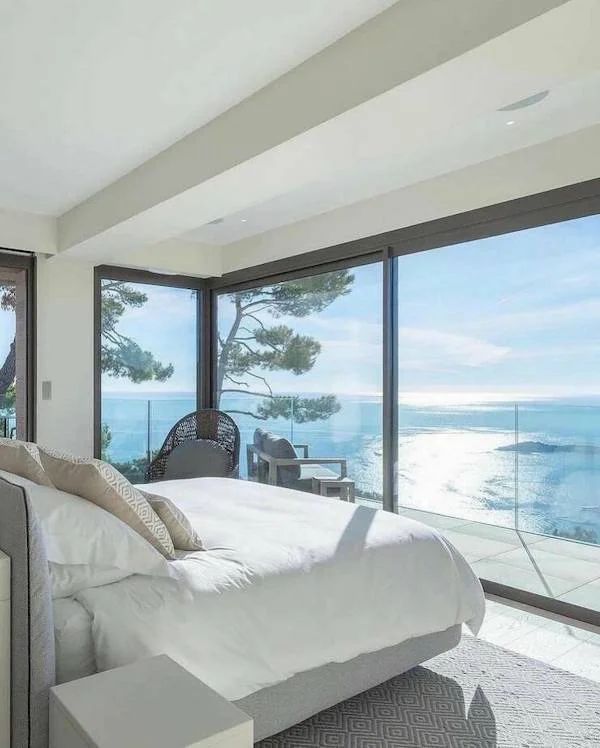 there is a large bed in the room with glass doors leading out to the ocean