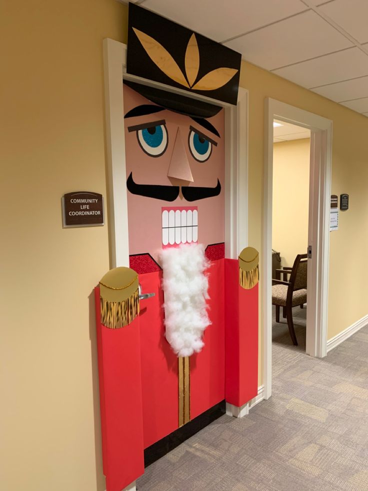 a large cardboard nutcracker is on display in an office hallway with the door open