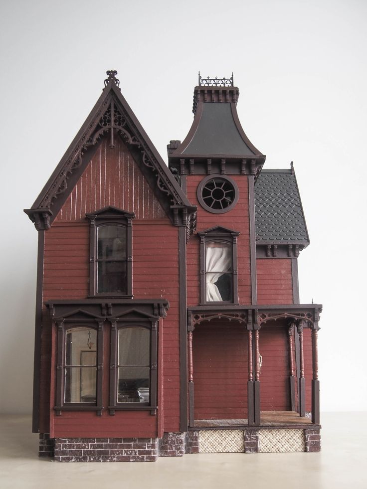 a red doll house with a clock on the front and side of it's roof