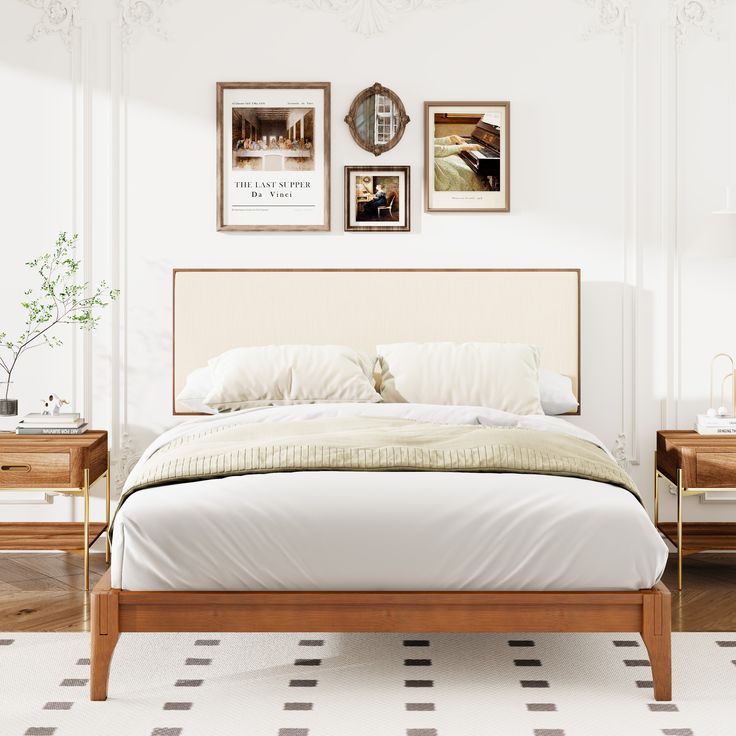 a bed with white sheets and pillows in front of two pictures on the wall above it