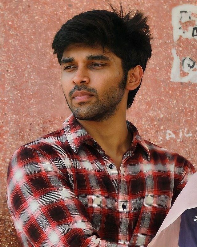 a man standing in front of a wall with his arms crossed and looking at the camera