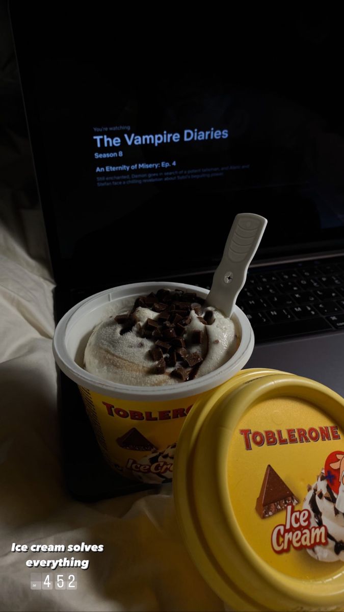 an ice cream sundae next to a laptop computer