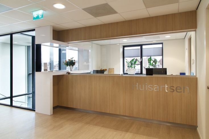 the front desk of a modern office with wood floors and glass doors on both sides