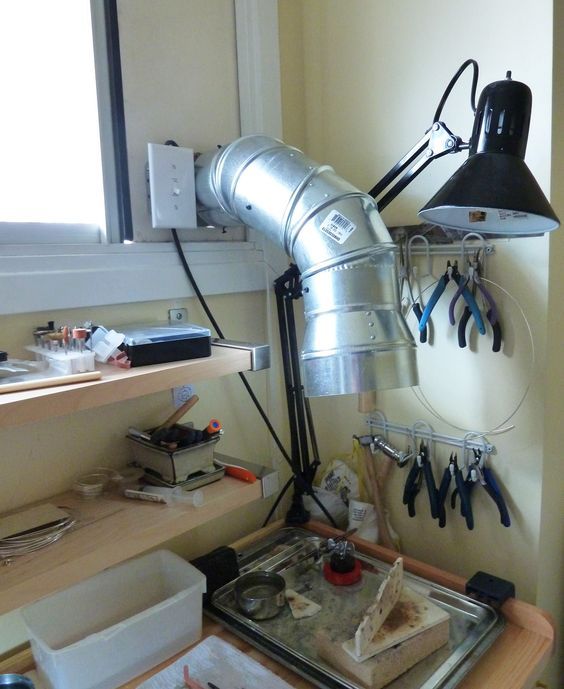 a workbench with tools hanging on the wall and an industrial light fixture above it