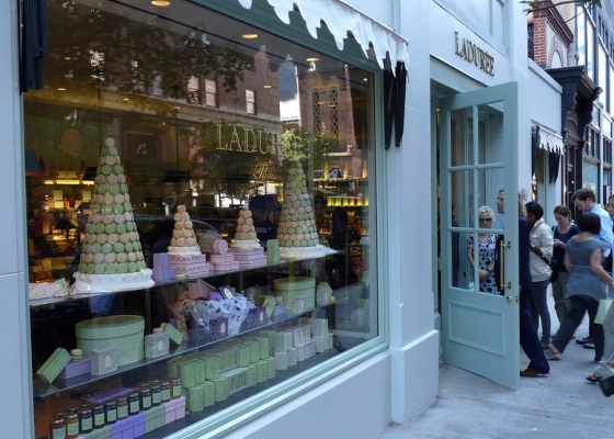 people are walking by a store front with cakes in the window and on the sidewalk