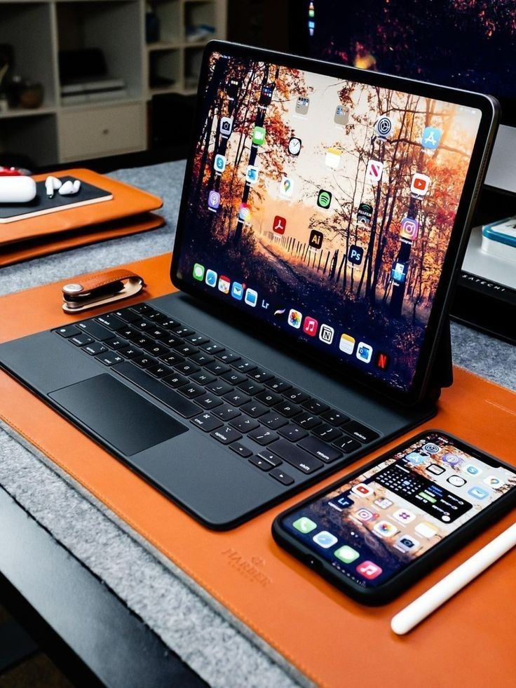 an open laptop computer sitting on top of a desk next to a cell phone and tablet