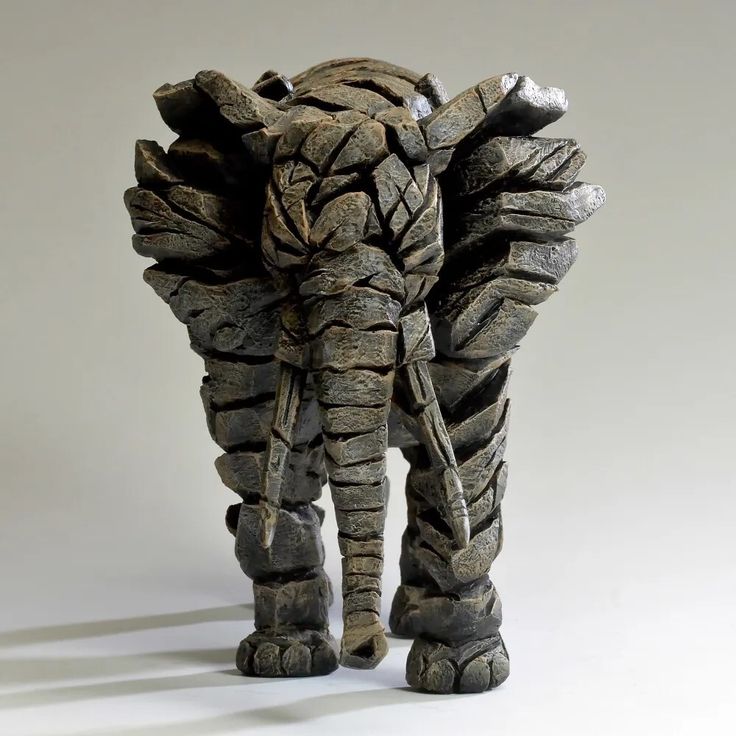 an elephant statue made out of rocks on a white background with shadow from the back