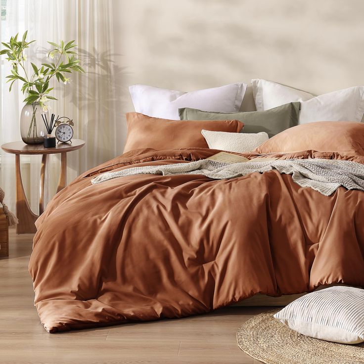 a bed with an orange comforter and pillows