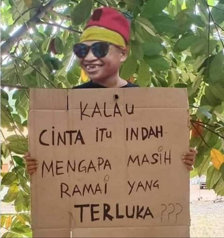 a person holding a sign that says i kalu cinta itu indah mengapa mash rama yang terlu?