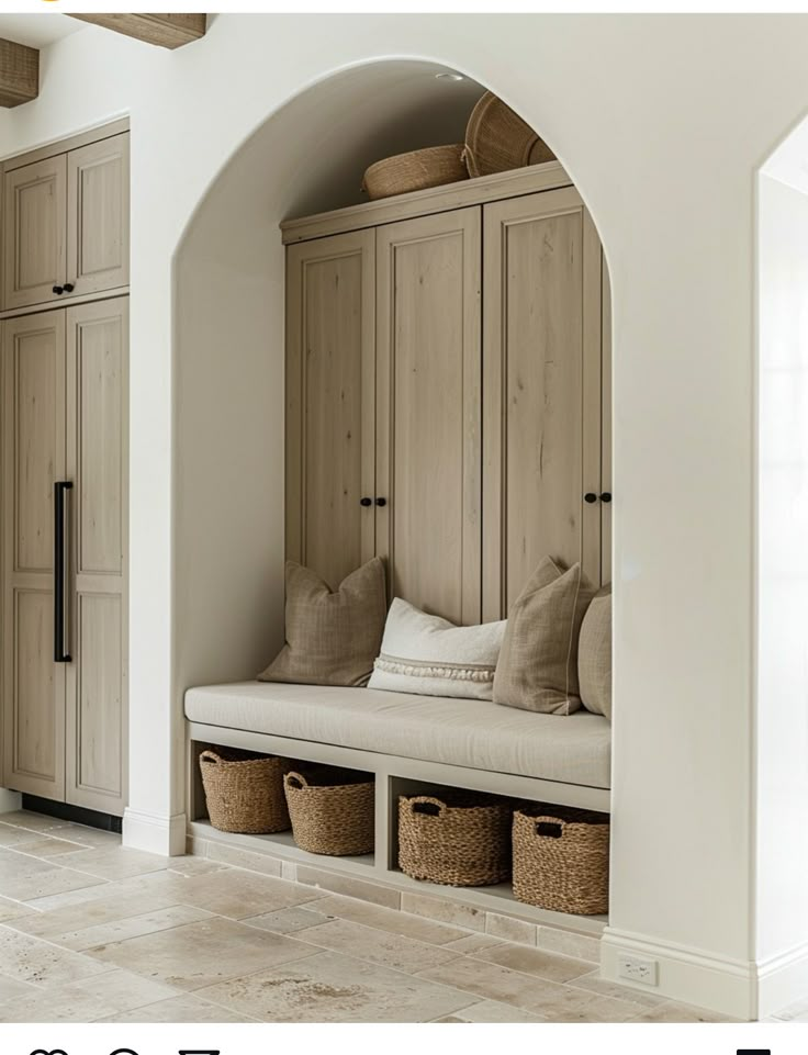 an arched entryway with built - in benches and storage baskets on the wall, along with large wooden cabinets