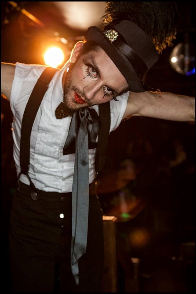 a man dressed in black and white is posing for the camera while wearing a top hat