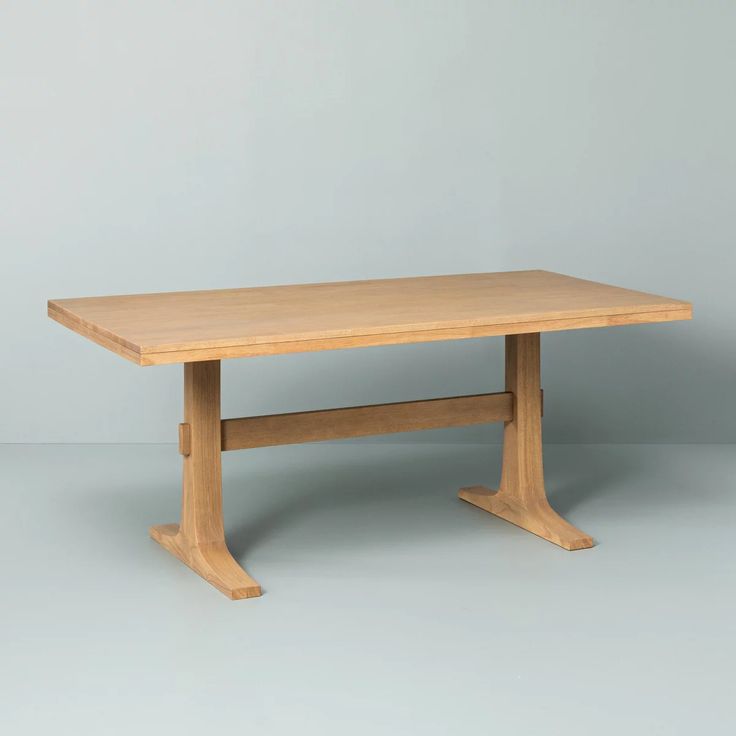 a wooden table sitting on top of a white floor next to a gray wall in an empty room