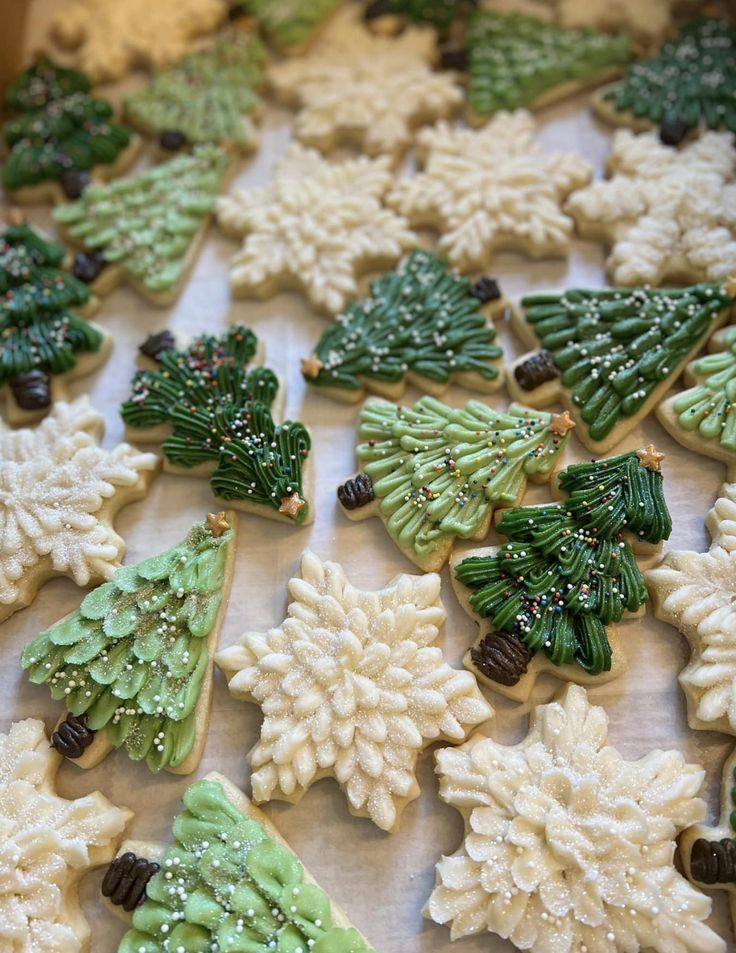 decorated cookies are arranged on a table with frosting and icing around the trees